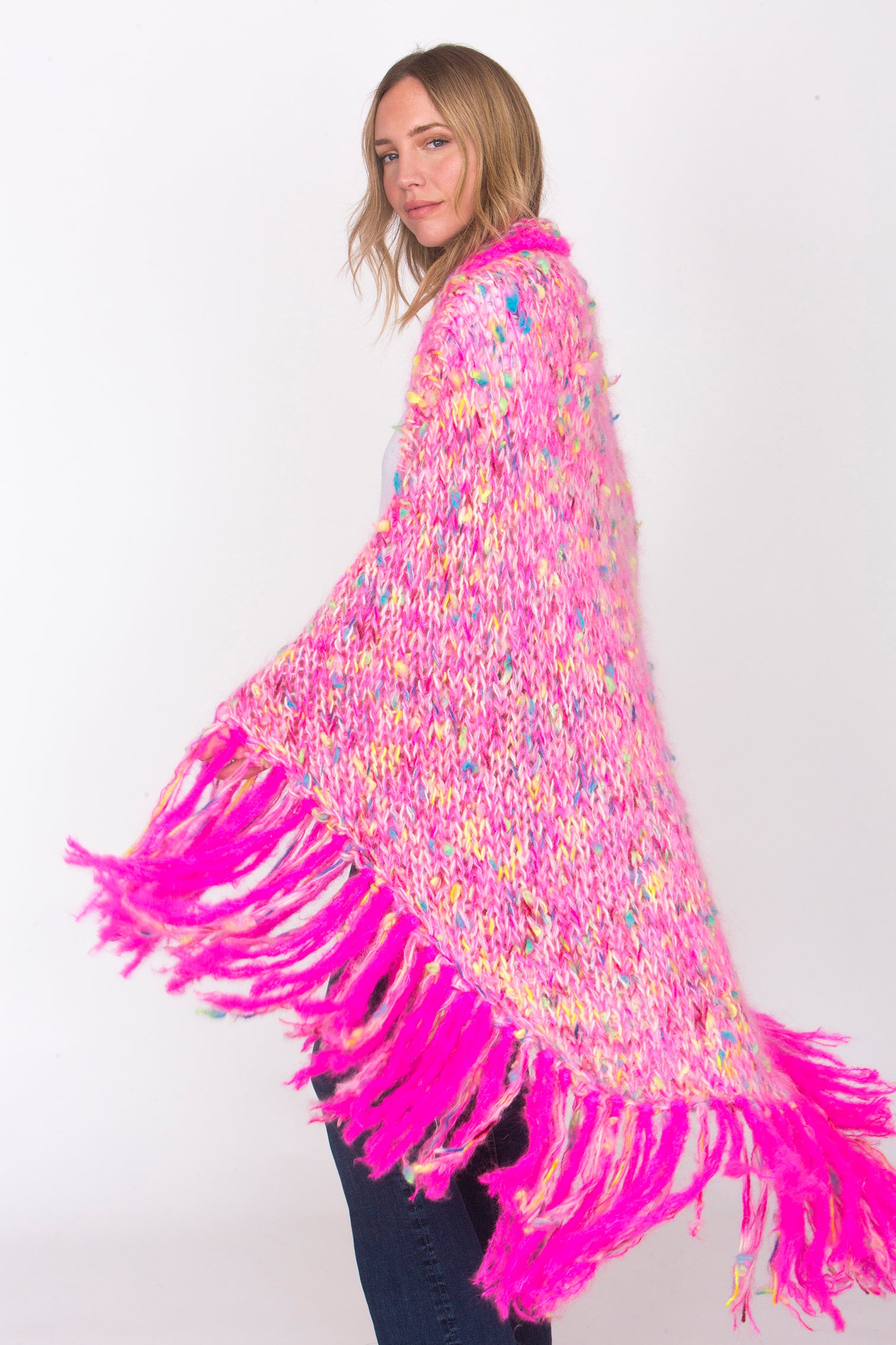 Our Aponi poncho, hangs luxurioulsy over your shoulders. Bright pink tassles, pink body with multicolour accents. Cosy, comfortable, soft.
